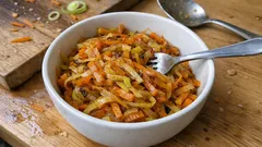 Polska surówka z marchewki i pora w misce na drewnianym stole, widoczny widelec.