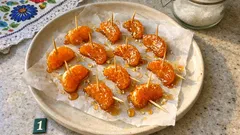 Kawałki kurczaka w panierce na wykałaczkach, przygotowane na papierze do pieczenia.