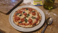 Pizza Margherita z pomidorami, mozzarellą i bazylią na talerzu, na drewnianym stole kuchennym
