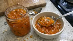 Domowy ajwar w miseczce i słoiku na kuchennym blacie, łyżka z pastą warzywną.