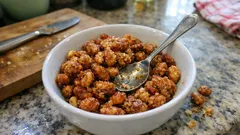 Prażona ciecierzyca z przyprawami w białej misce na kuchennym blacie, łyżka w środku.