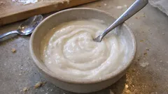 Domowy jogurt naturalny w miseczce z łyżką na kuchennym blacie.