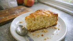 Kawałek domowego ciasta jabłkowego na białym talerzu z łyżką, domowe wypieki.