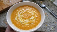 Zupa krem z dyni w misce, udekorowana jogurtem, na kuchennym blacie