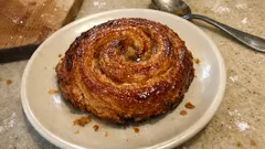 Duńska drożdżówka śniadaniowa z cynamonem na białym talerzu, widok z góry