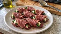 Roladki z wołowiny nadziewane serem i warzywami, podane na białym talerzu.