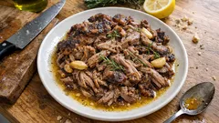 Duszona jagnięcina z ziołami i czosnkiem na białym talerzu, domowa kuchnia polska.