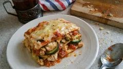 Lasagne warzywna na talerzu, widoczne plastry cukinii i sos pomidorowy, świeża porcja.