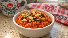 Miseczka indyjskiego deseru gajar ka halwa z marchewką, orzechami i przyprawami na blacie kuchennym.