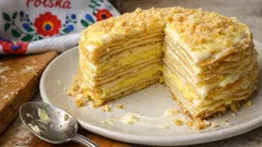 Polskie ciasto warstwowe z kremem na białym talerzu, kawałek już odkrojony.