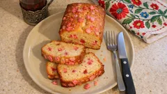 Ciasto z kolorową posypką na talerzu, obok widelec, nóż i kwiecista serwetka.