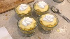 Deser budyniowy w pucharkach z bitą śmietaną, domowe słodkości na stole kuchennym.