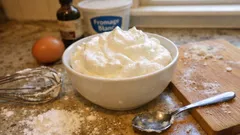 Świeża bita śmietana w misce na kuchennym blacie z jajkiem i składnikami do pieczenia.