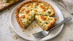 Tarta warzywna z serem pokrojona na kawałki na białym talerzu z widelcem.