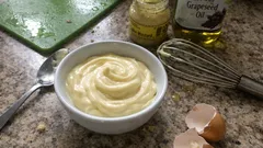 Domowy majonez w misce, składniki: jajka, olej, musztarda, trzepaczka na kuchennym blacie.