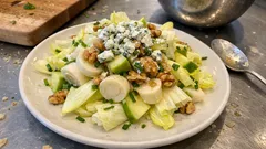 Sałatka Waldorf z selerem, jabłkiem, orzechami włoskimi i serem pleśniowym na białym talerzu.