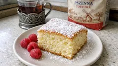 Ciasto ucierane z cukrem pudrem na talerzu, maliny, filiżanka herbaty, mąka pszenna w tle