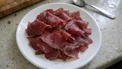 Plasterki suszonej wołowiny na białym talerzu na blacie kuchennym