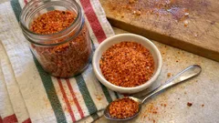 Domowa mieszanka przypraw w słoiku, miseczce i łyżce na kuchennym stole.