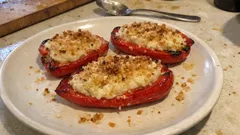 Grillowana papryka z serem i chrupiącą posypką na białym talerzu, kuchenny stół w tle