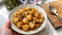 Pyzy ziemniaczane z cebulą i przyprawami na białym talerzu, domowe danie obiadowe