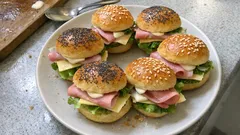 Bułki z szynką, serem i sałatą na talerzu, przekąski kanapkowe na imprezę