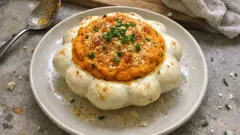 Pieczony patison faszerowany warzywami na białym talerzu, posypany ziołami.