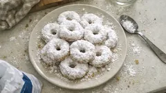 Pączki w kształcie pierścieni, posypane cukrem pudrem na talerzu, widok z góry