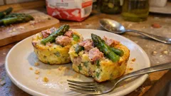 Mini frittaty z szynką i szparagami na talerzu, widelce obok, domowe śniadanie.