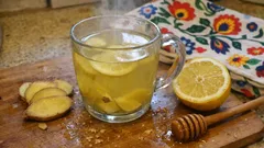 Herbata z imbirem, cytryną i miodem na desce kuchennej, świeże składniki obok.