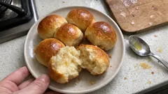 Słodkie bułeczki drożdżowe na talerzu, jedna przełamana, domowa kuchnia, świeże pieczywo.