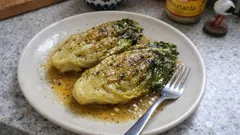 Pieczona sałata rzymska z przyprawami na białym talerzu, widelcem i sosem.