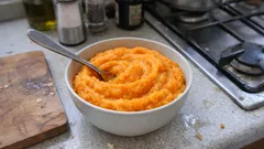 Puree z batatów w misce na kuchennym blacie, widoczne przyprawy i kuchenka w tle