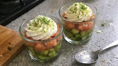 Tatar z łososia z awokado i kremem w szklankach na kuchennym blacie