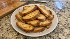 Chrupiące grzanki na białym talerzu, podane na kamiennym blacie kuchennym