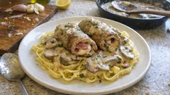 Roladki wołowe z grzybowym sosem na tagliatelle na białym talerzu, kuchnia domowa