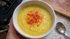 Zupa krem z kukurydzy w misce, posypana papryką, na tle kuchennego blatu.