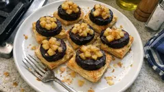 Kaszanka na cieście francuskim z jabłkami na białym talerzu, widelce obok, domowe śniadanie