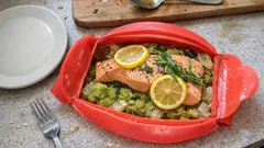 Pieczony łosoś z cytryną i koperkiem w czerwonym naczyniu, na kapuście, kuchnia domowa.