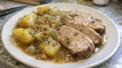 Duszona pieczeń z ziemniakami i cebulą na białym talerzu, tradycyjny polski obiad.