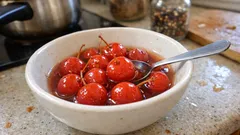 Wiśnie w syropie w białej miseczce na kuchennym blacie, łyżka, domowa konfitura